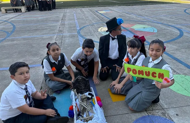 Alumnos de primaria junto al altar de Día de Muertos que montaron en el patio