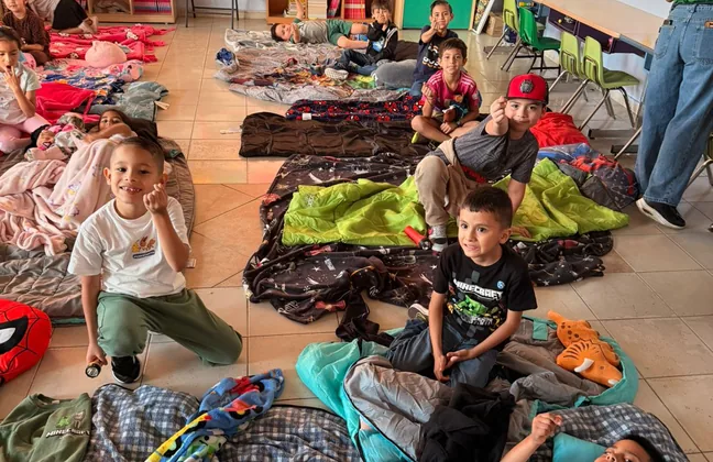 Alumnos de primaria mayor en sus sleeping bags durante el campamento